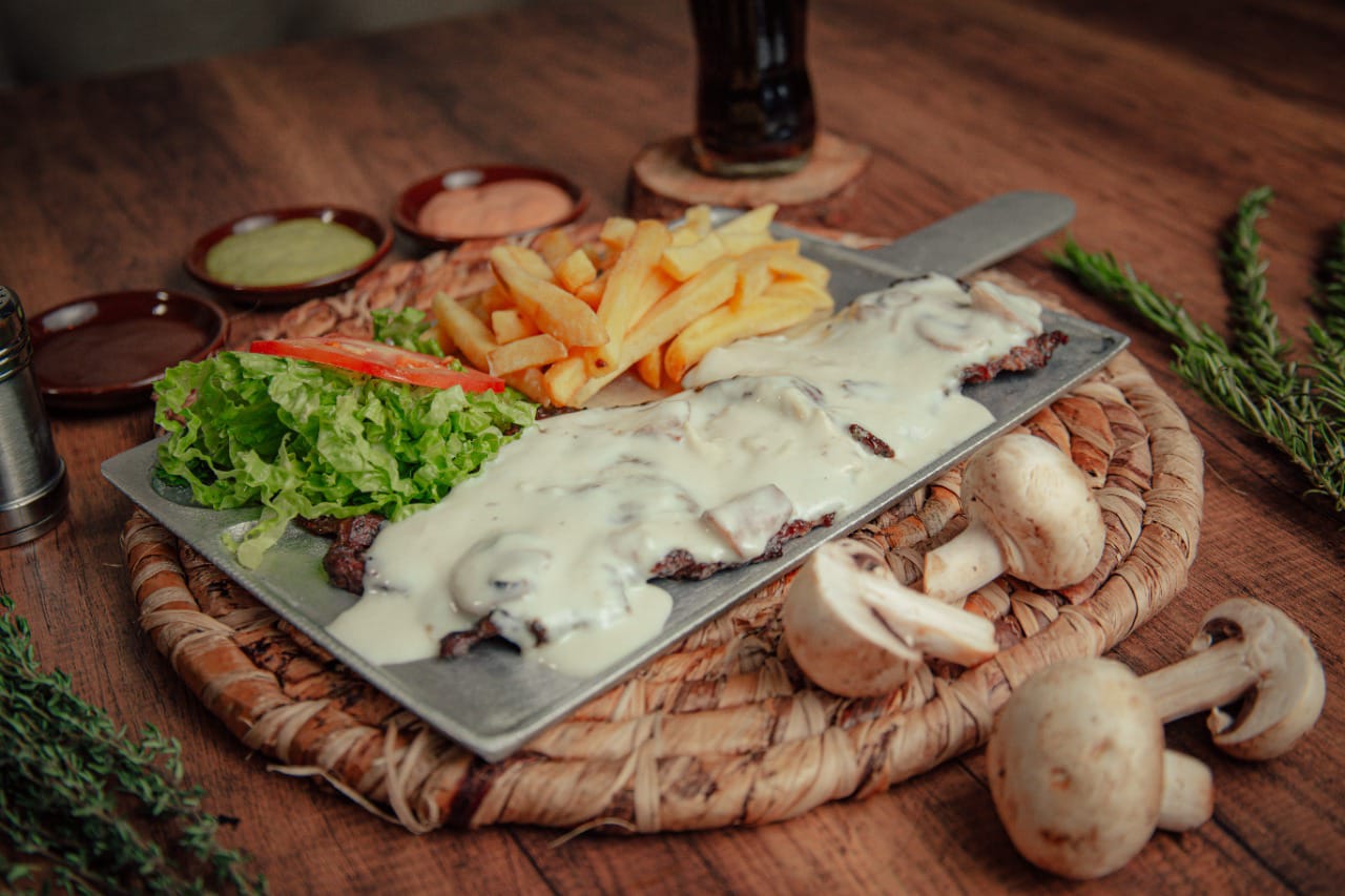 Carne a la brasa con salsa de champiñones y papas